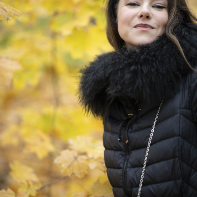 Naturalny portret uśmiechniętej Anny ze złotymi liśćmi w tle w toruńskim parku, w stylu beauty