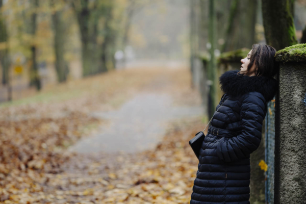 Anna w zimowym stroju, stojąca na tle alejki w toruńskim parku, w nastrojowym świetle popołudnia.