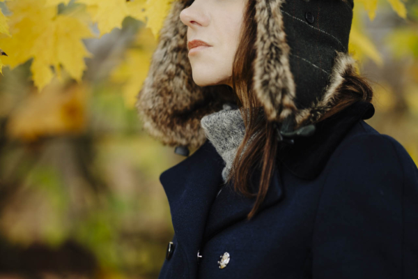 Anna w zimowym stroju, stojąca na tle alejki w toruńskim parku, w nastrojowym świetle popołudnia.