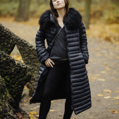 Anna w zimowym stroju, stojąca na tle alejki w toruńskim parku, w nastrojowym świetle popołudnia.