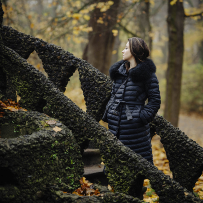 Anna w zimowym stroju, stojąca na kamiennych schodach w toruńskim parku, w nastrojowym świetle popołudnia.