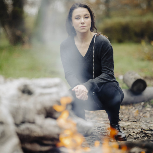 Anna siedząca przy płonącym ognisku, oświetlona ciepłym blaskiem płomieni w parku na Bydgoskim Przedmieściu w Toruniu