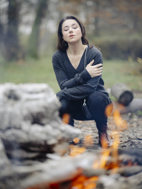 Anna siedząca przy płonącym ognisku, oświetlona ciepłym blaskiem płomieni w parku na Bydgoskim Przedmieściu w Toruniu